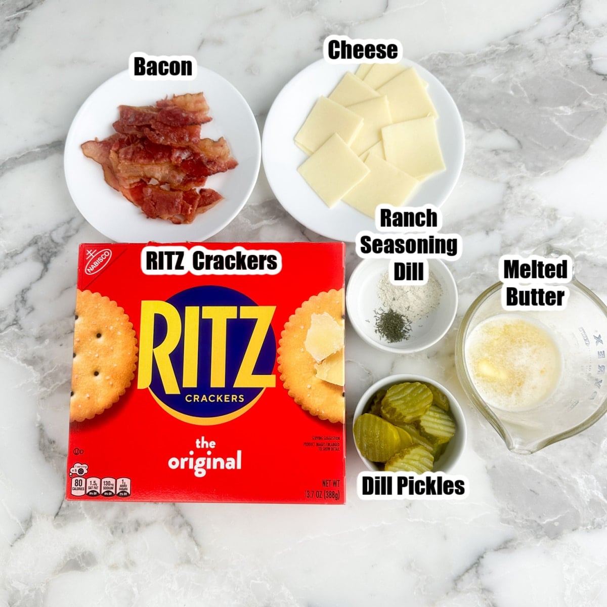 Box of Ritz crackers, plate of bacon, sliced cheese, pickles, seasonings, and melted butter.