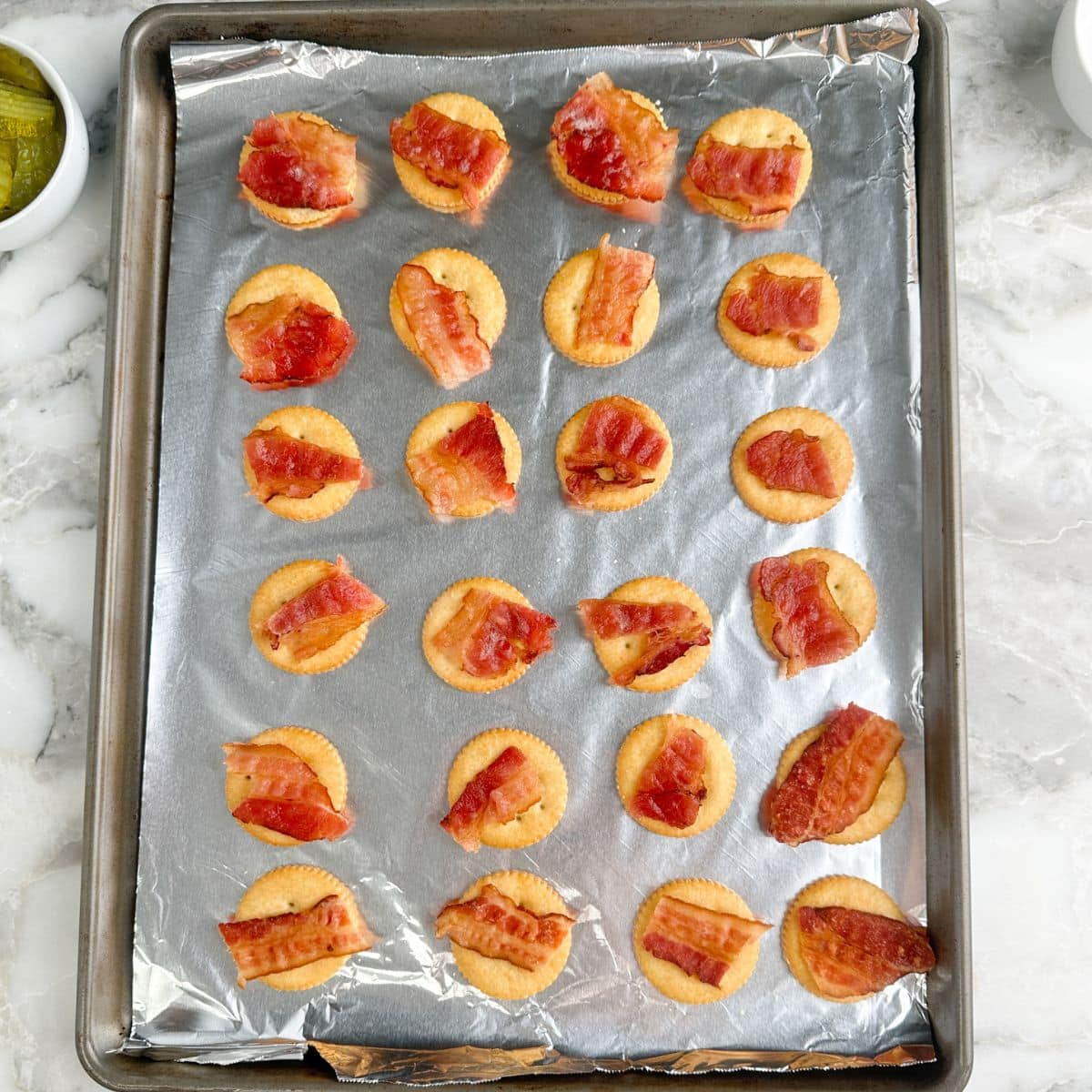 Baking pan with Ritz crackers topped with bacon.