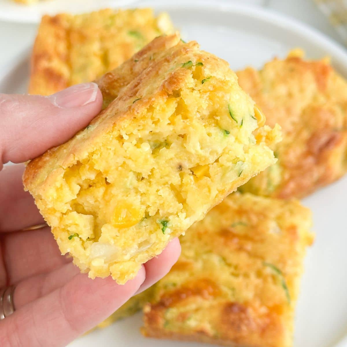 Hand holding zucchini cornbread. 