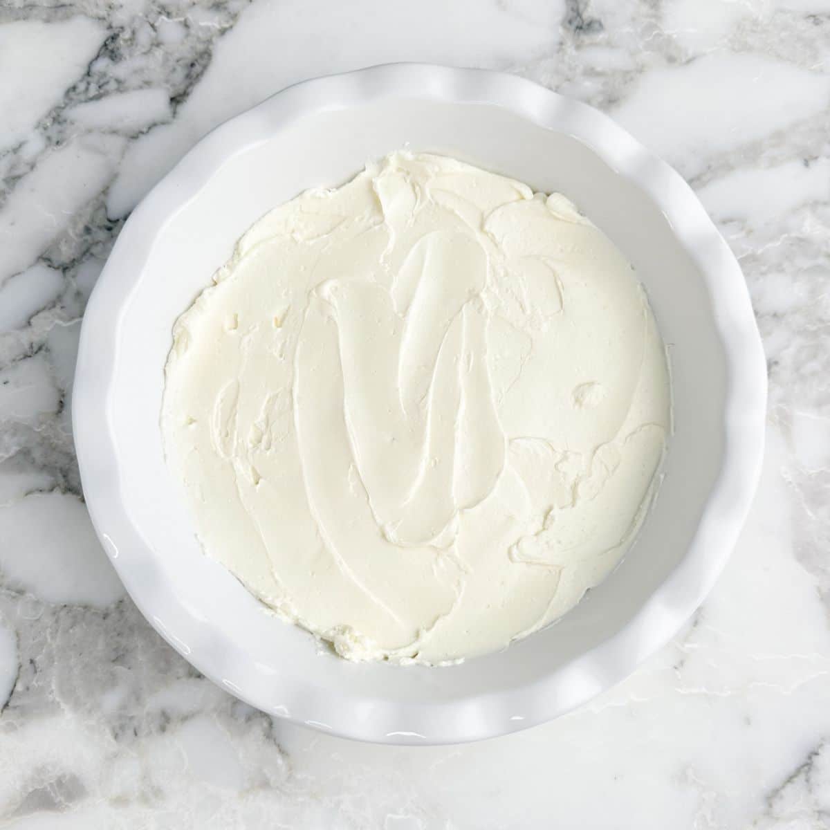 Baking dish with cream cheese spread out. 