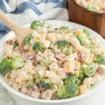 Bowl filled with broccoli pasta salad and wooden spoon.