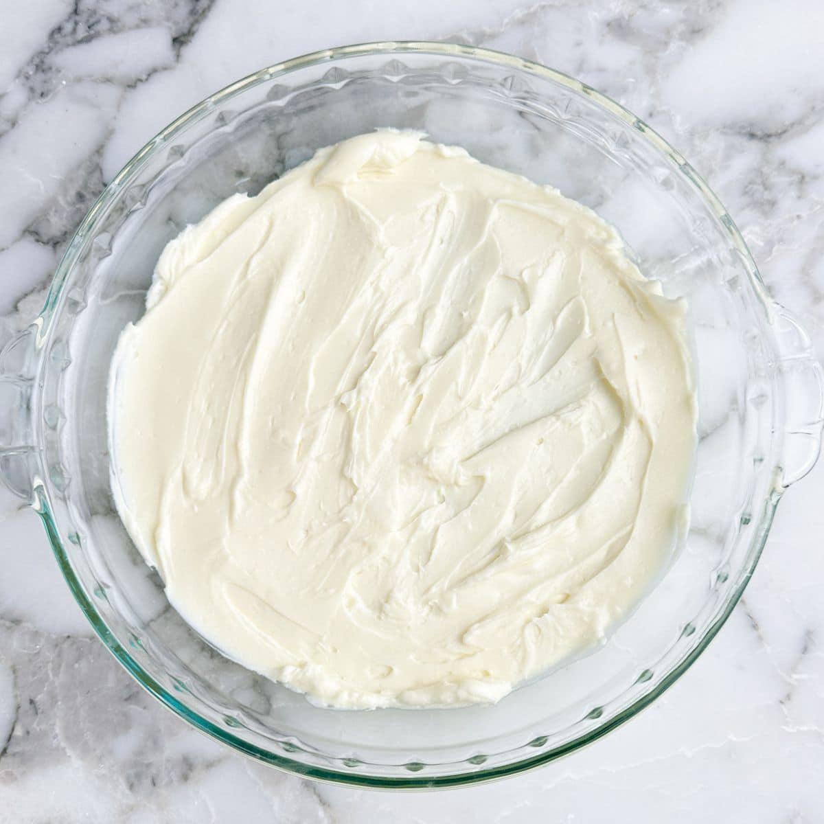 Pie dish with cream cheese spread out. 