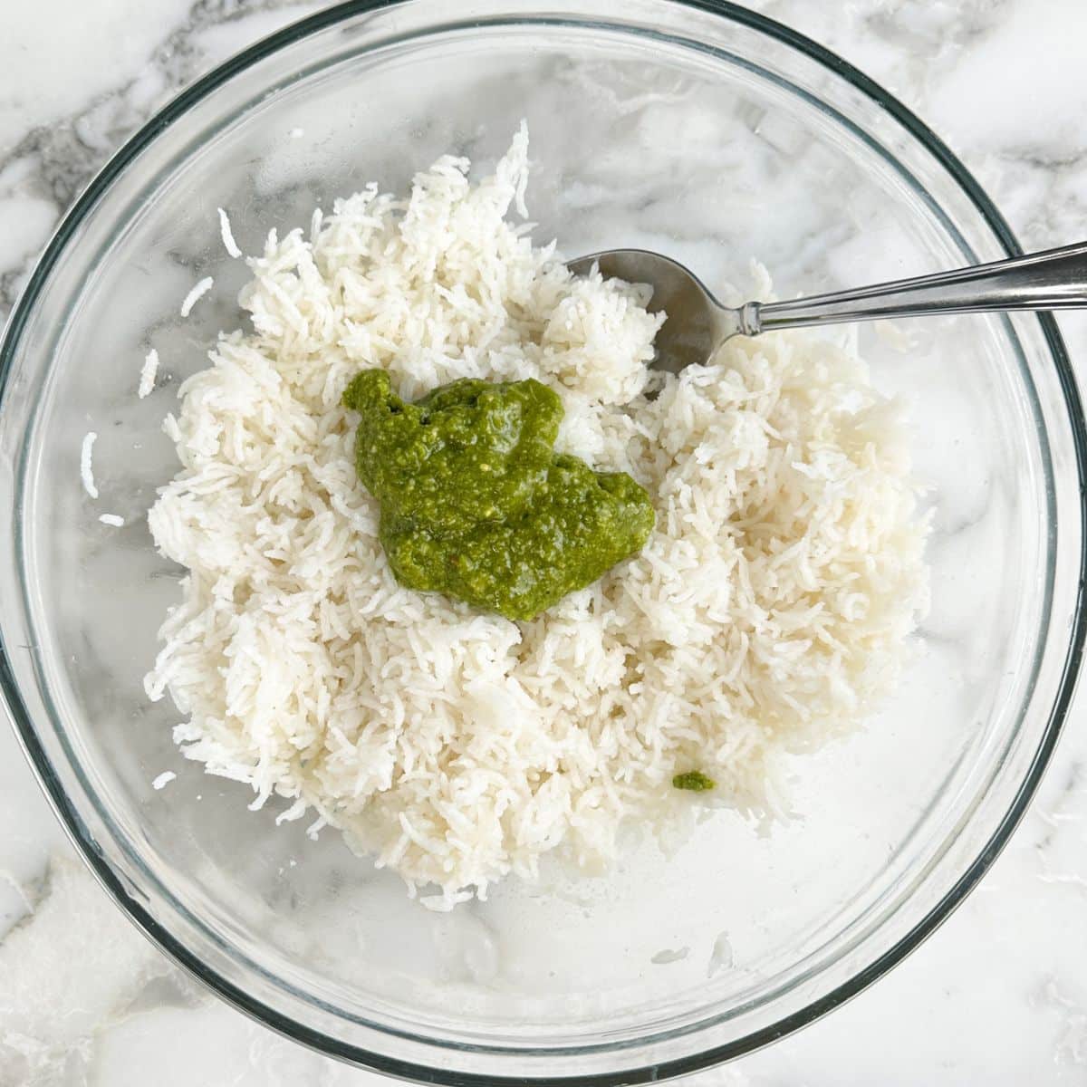 Bowl of basmati rice with pesto sauce and a spoon. 