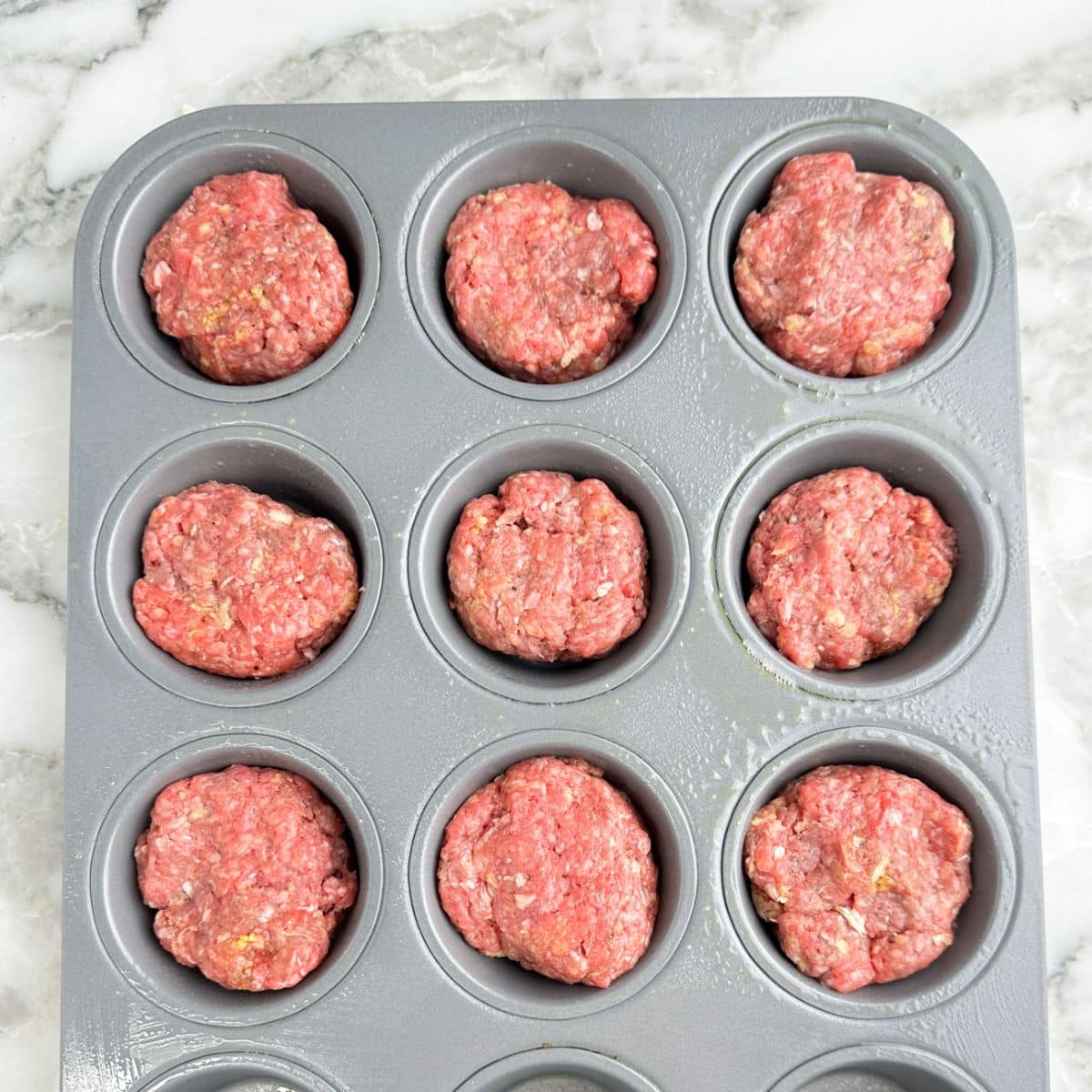 Muffin tin with unbaked meatloaf mixture.