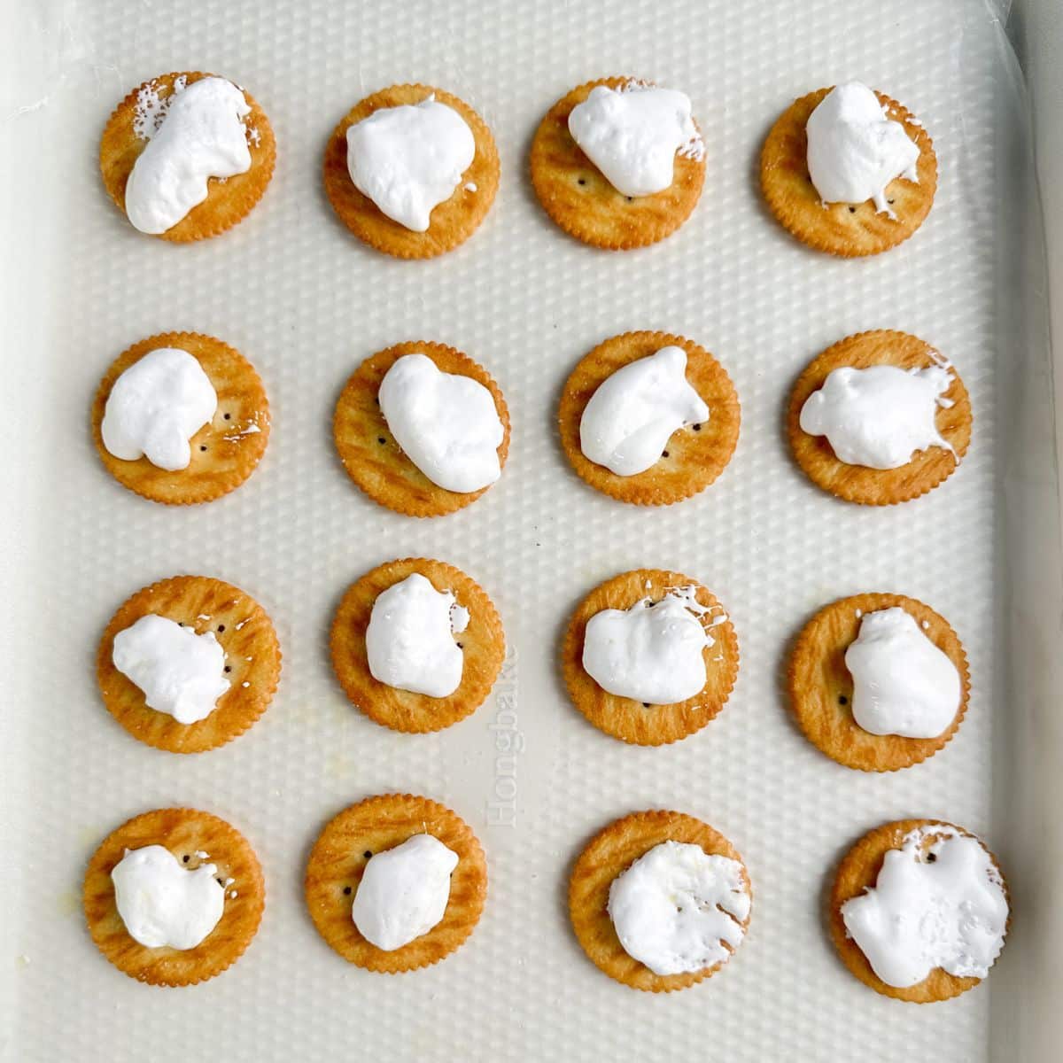 Ritz crackers topped with marshmallow creme on a cookie sheet.