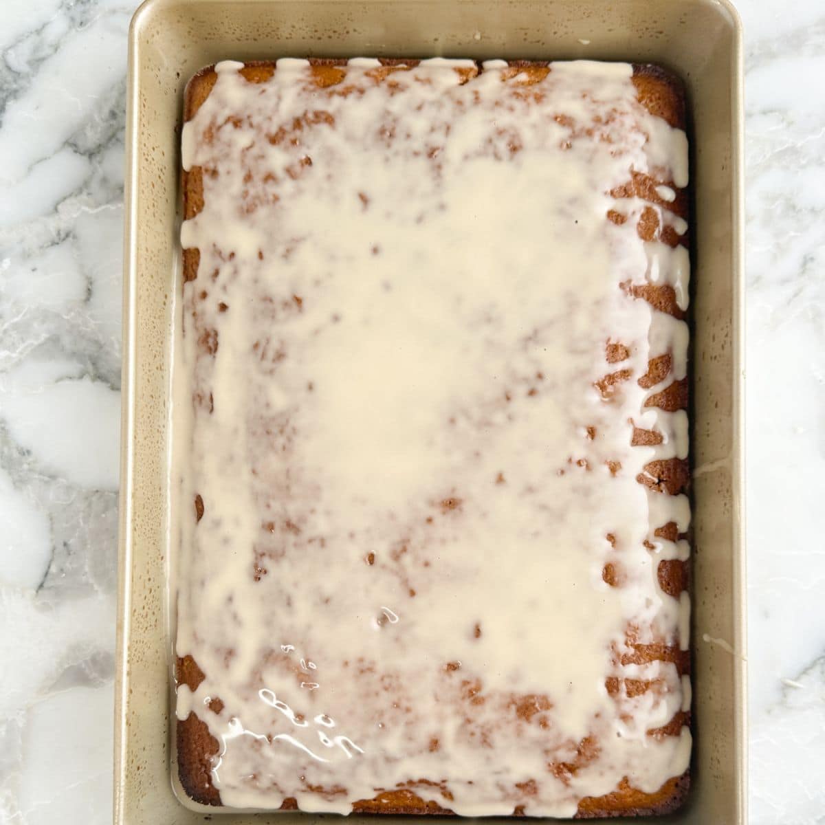 Baking pan with baked root beer cake topped with icing.