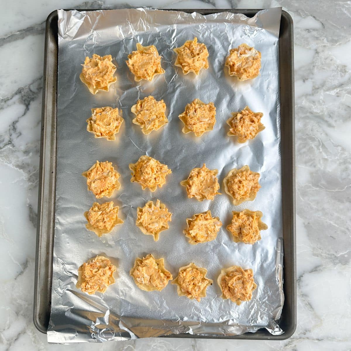 Baking dish with unbaked buffalo chicken dip bites.