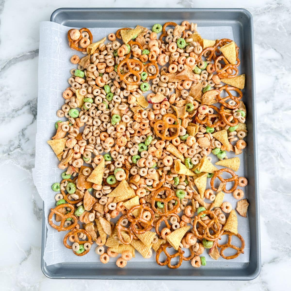 Cereal snack mix on a baking sheet.