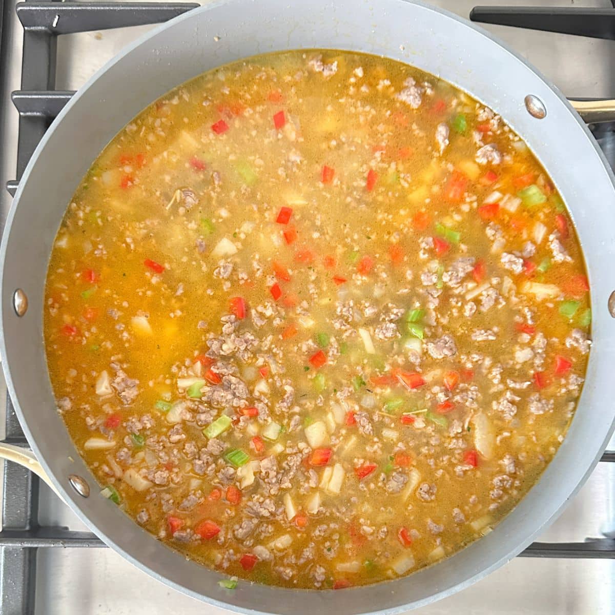 Skillet with broth, rice, and vegetables.