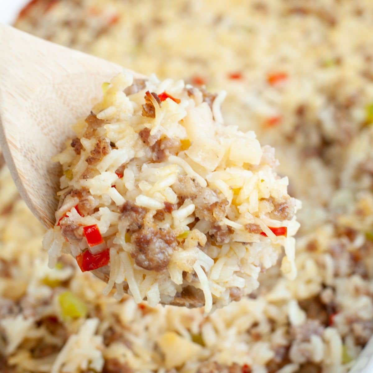 Wooden spoon with sausage and rice casserole.