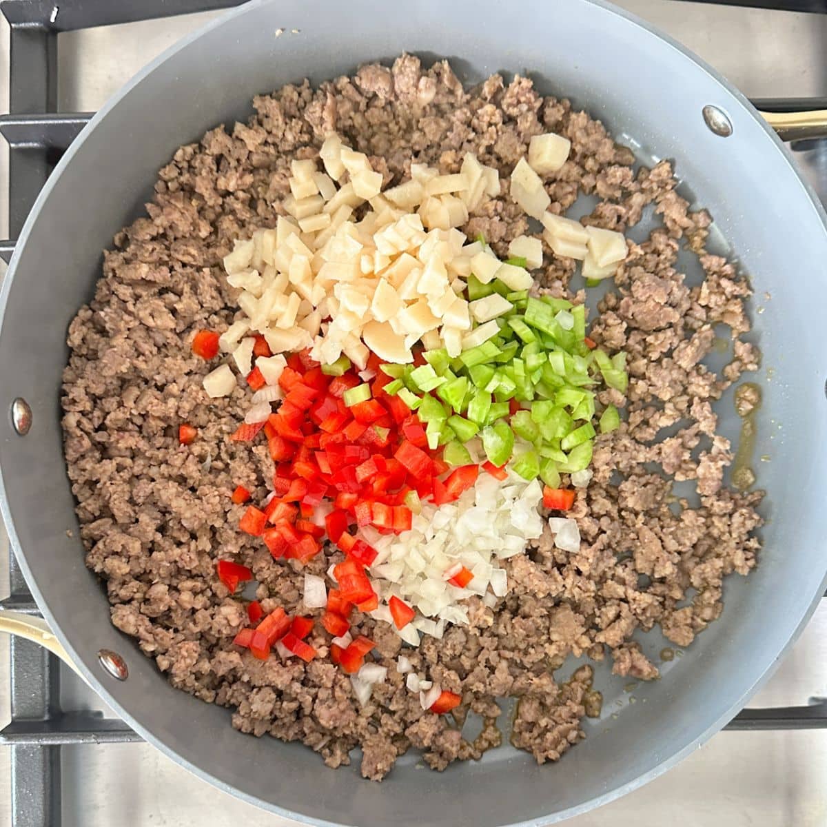 Skillet with ground sausage, diced pepper, celery, onion, and water chestnuts.