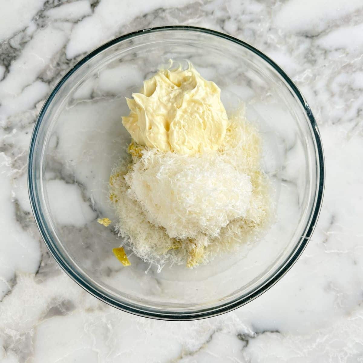 Bowl of artichoke hearts, mayonnaise, and grated parmesan cheese.
