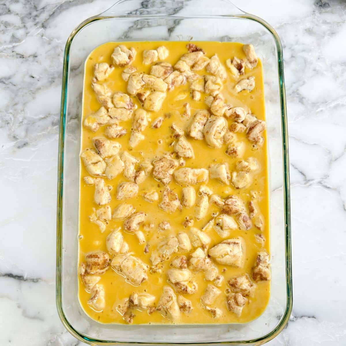 Baking dish with uncooked orange roll casserole.