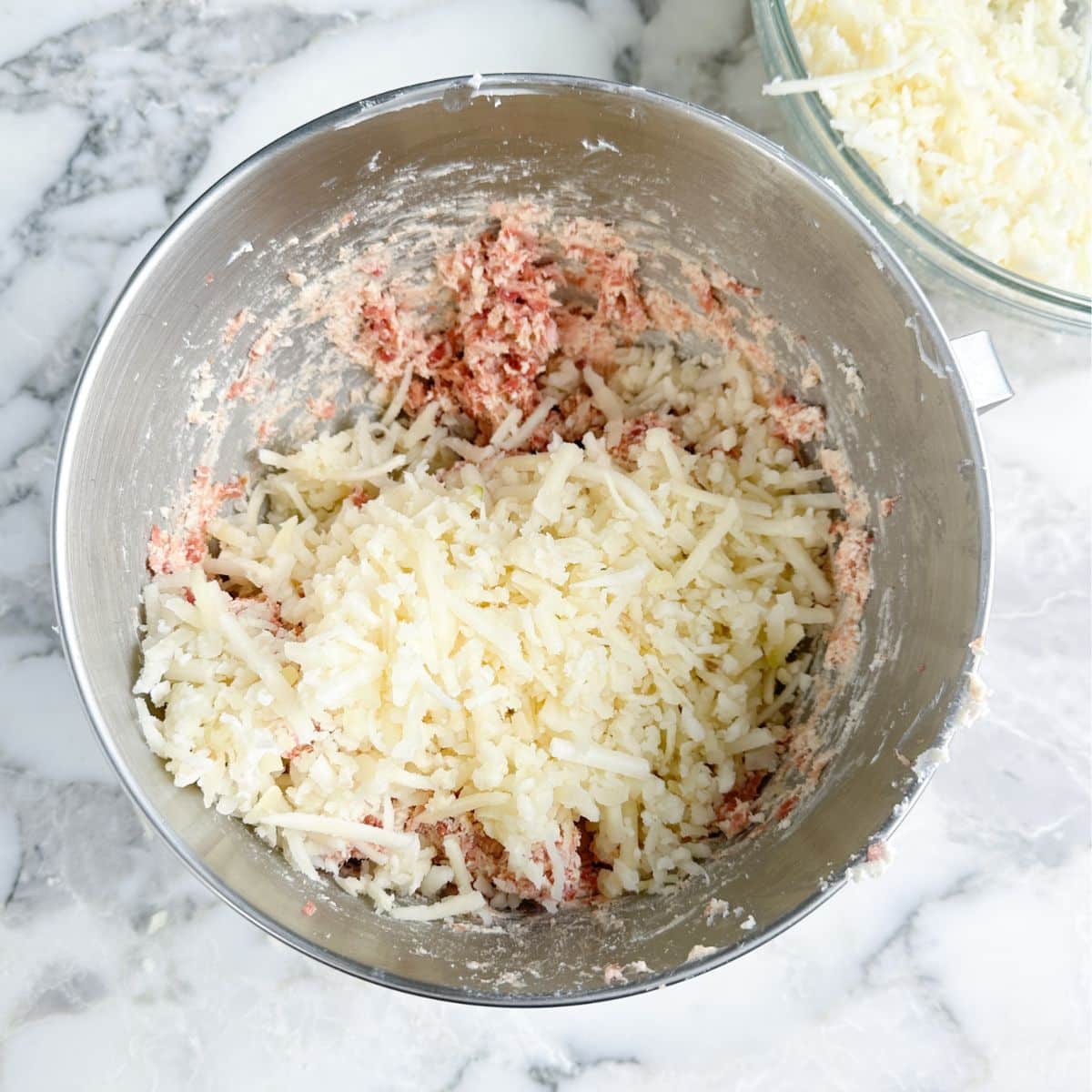 Mixing bowl with sausage, hash browns, and cream cheese.