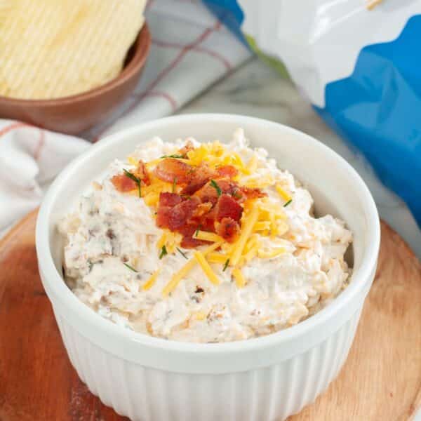Bowl of loaded baked potato dip and potato chips.