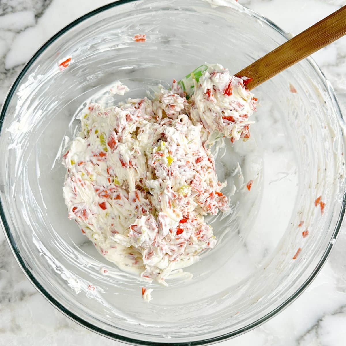 Bowl of mixed pepperoni dip with a spatula. 
