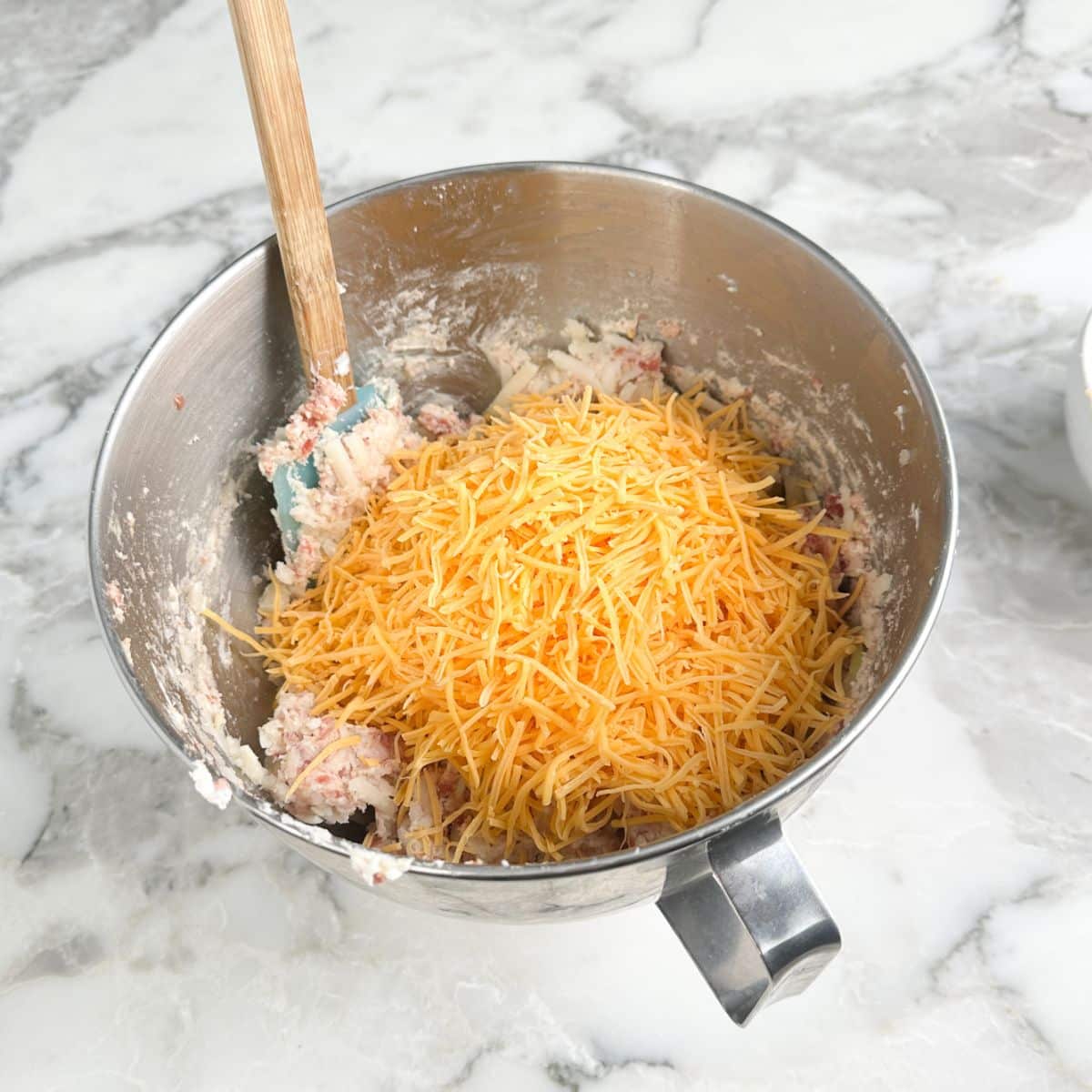 Sausage, hash browns, and shredded cheese in a mixing bowl.