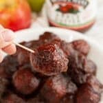 Hand holding a toothpick with a meatball on it.