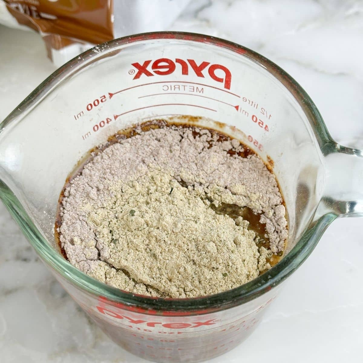 Measuring cup with beef broth and seasonings.