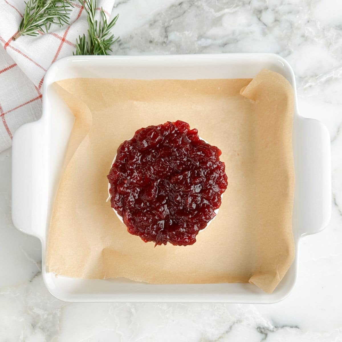 Baked brie topped with cranberry sauce in a baking dish.