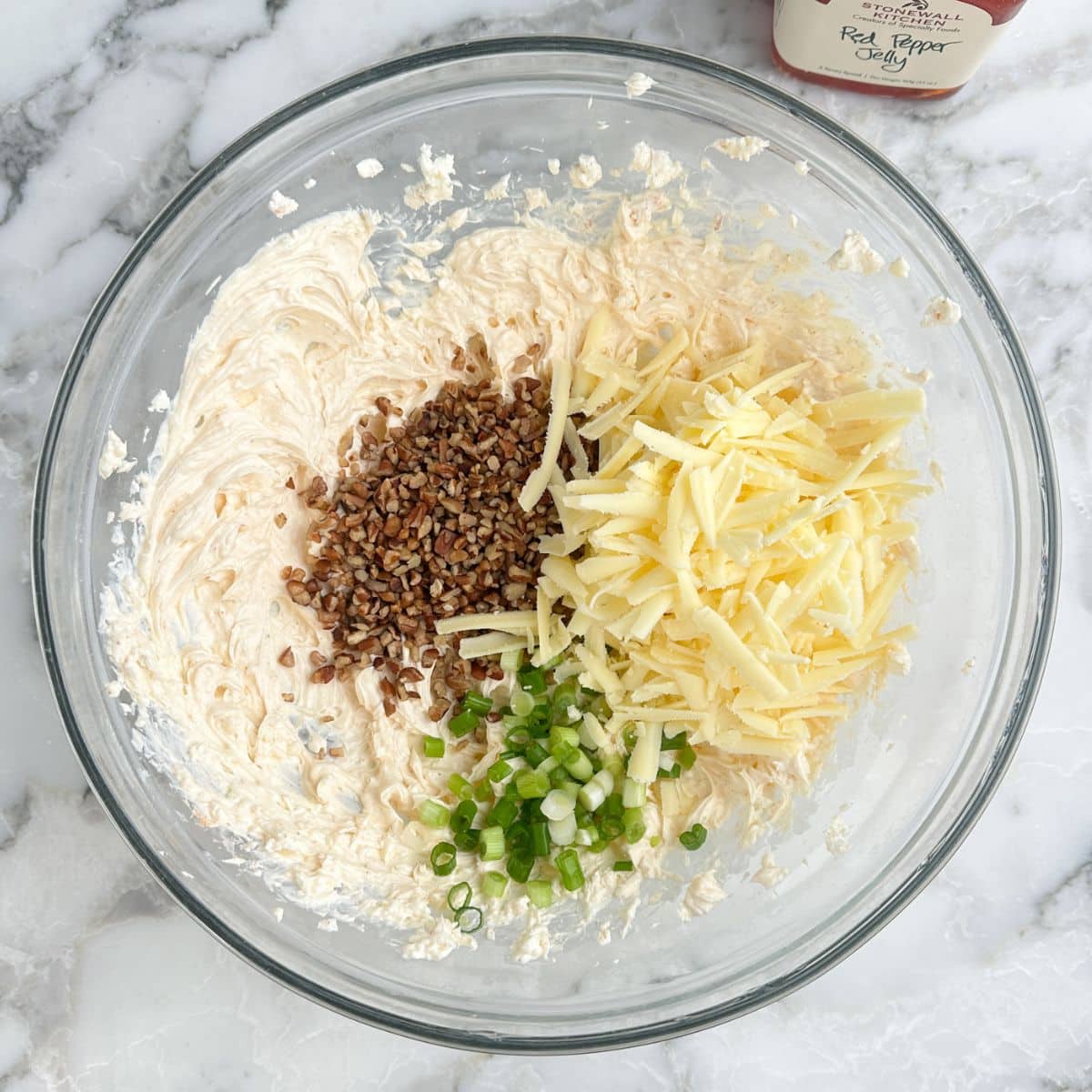 Bowl with whipped cream cheese, shredded cheese, green onions, and chopped pecans.