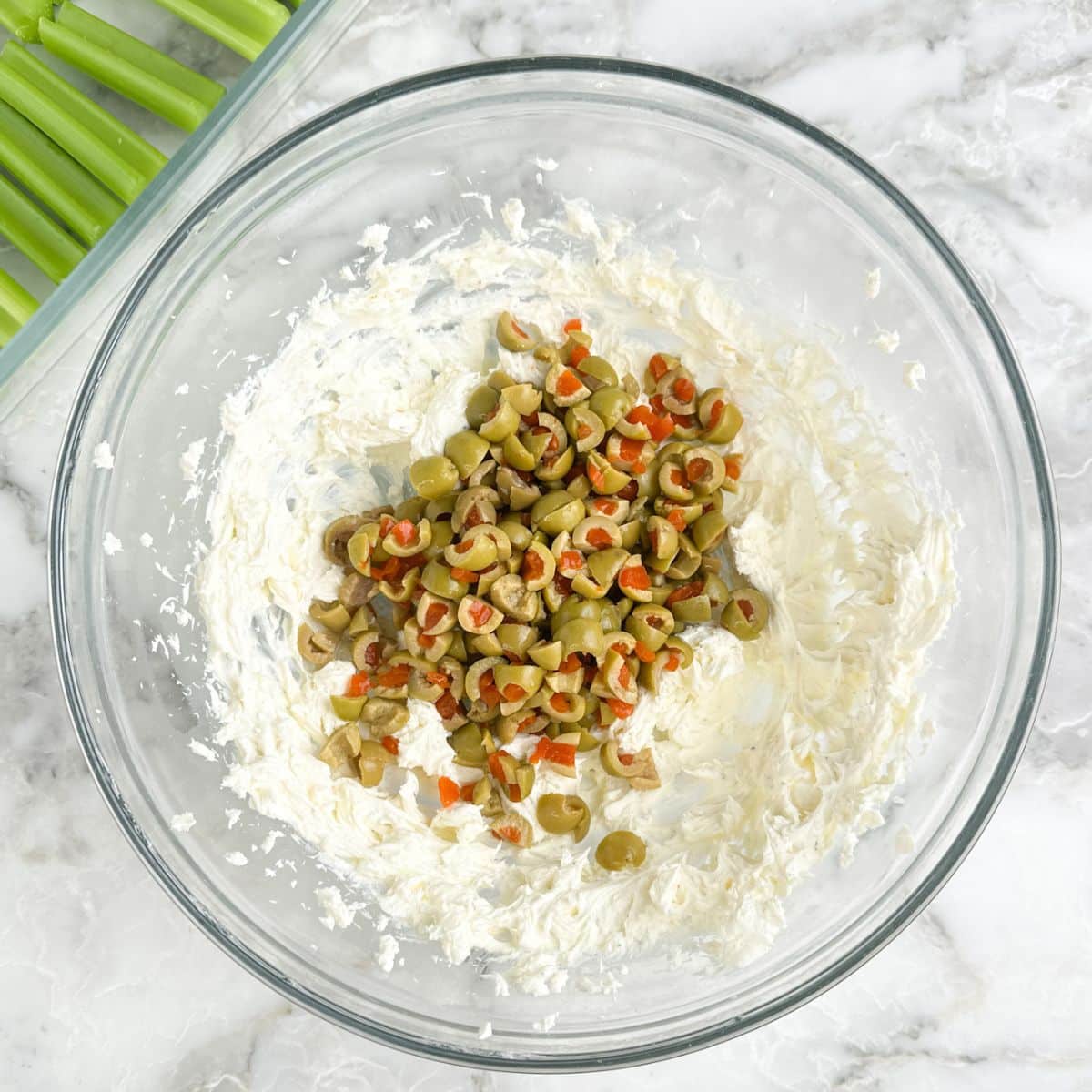 Bowl with whipped cream cheese and chopped olives. 
