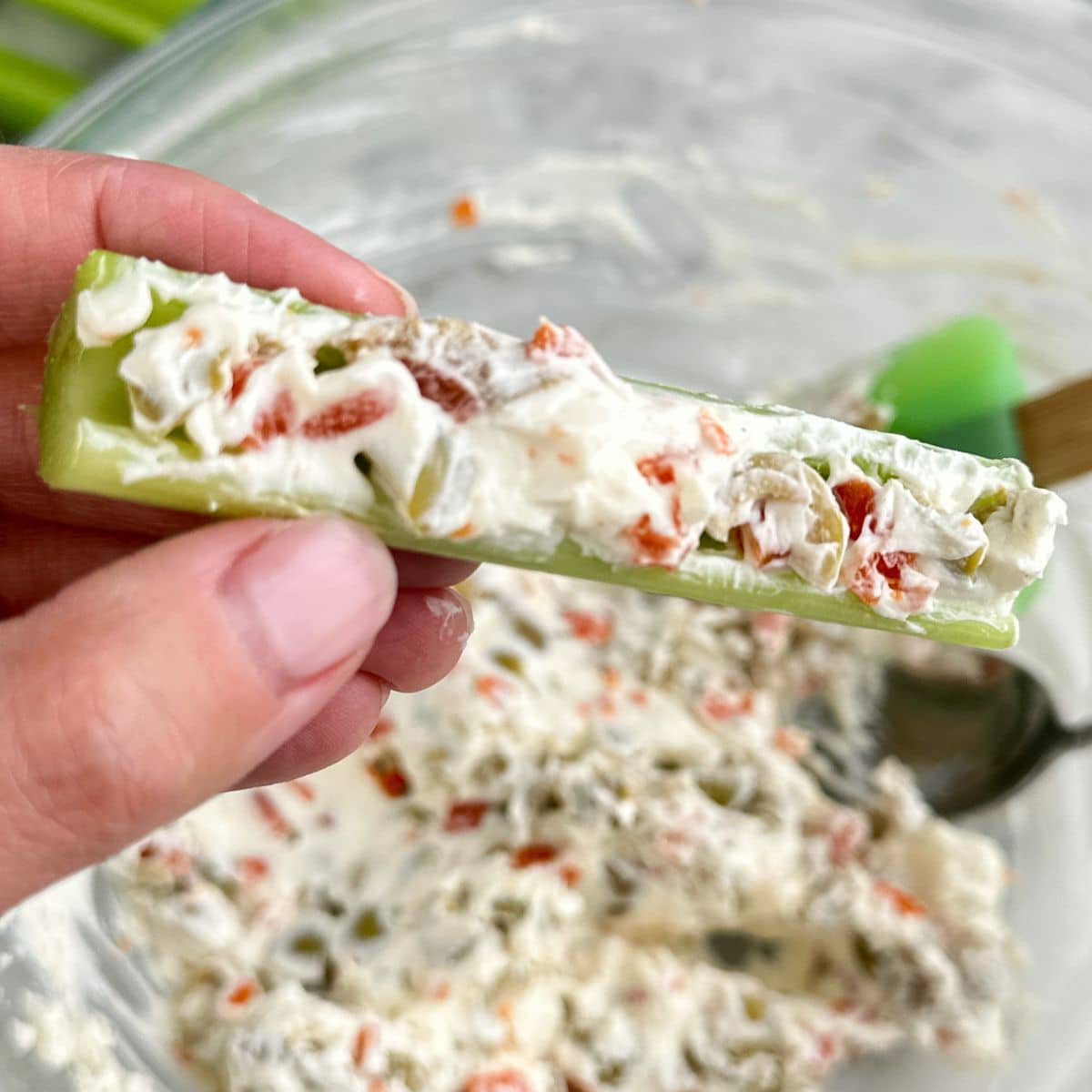Hand holding olive stuffed celery stick.
