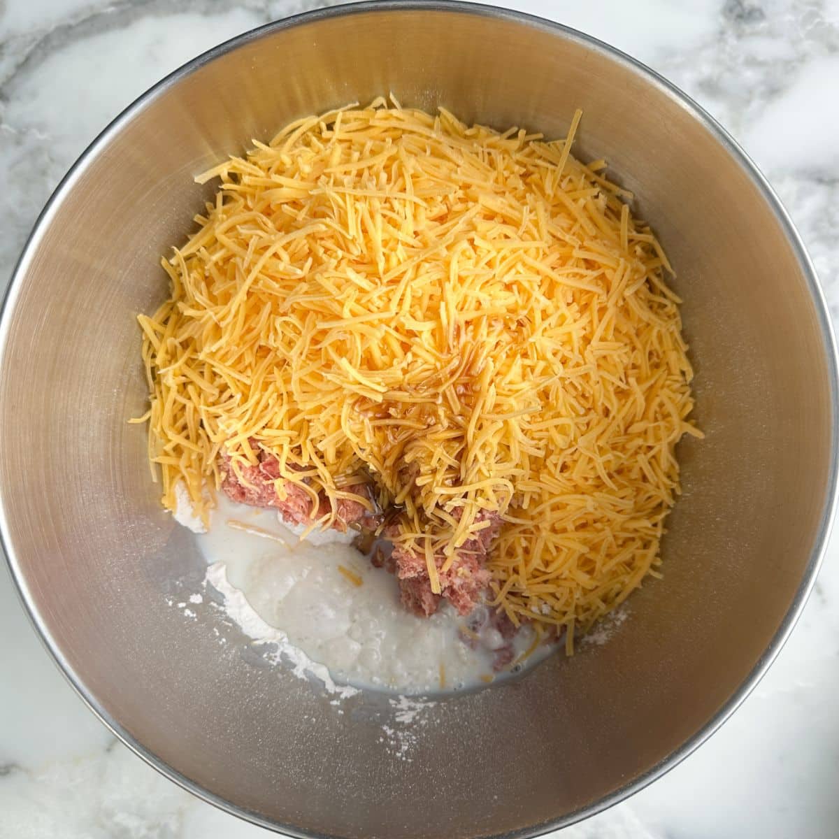 Mixing bowl with pancake mix, sausage, and shredded cheese.