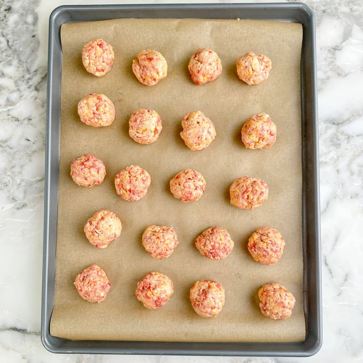 Baking sheet with uncooked sausage balls.