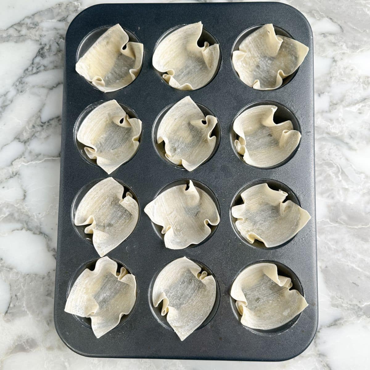Muffin tin with wonton wrappers.